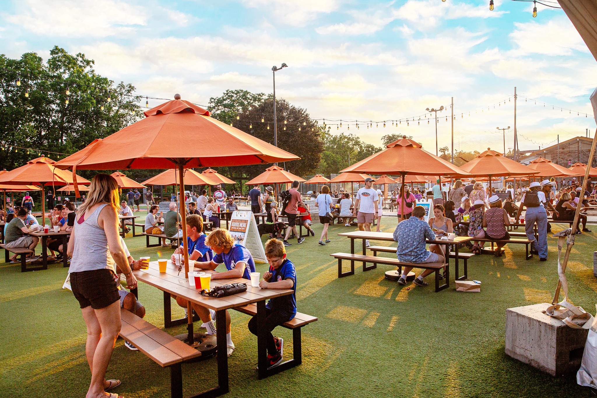 Sunset over the Fifty West beer garden full of guests at picnic tables