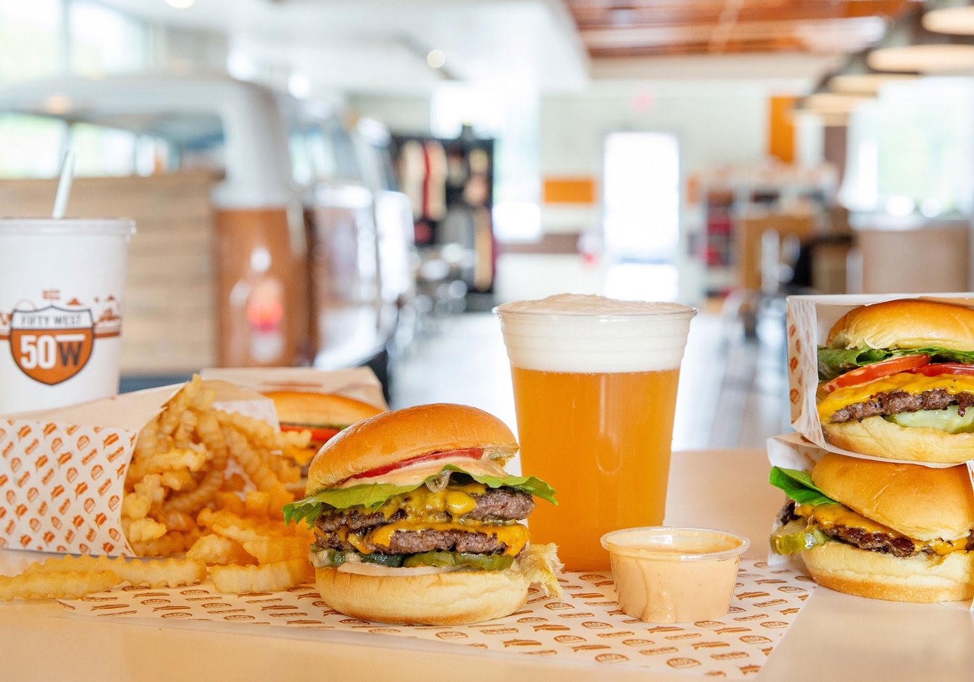 Fifty West burgers, crinkle fries, beer, and shake on a counter