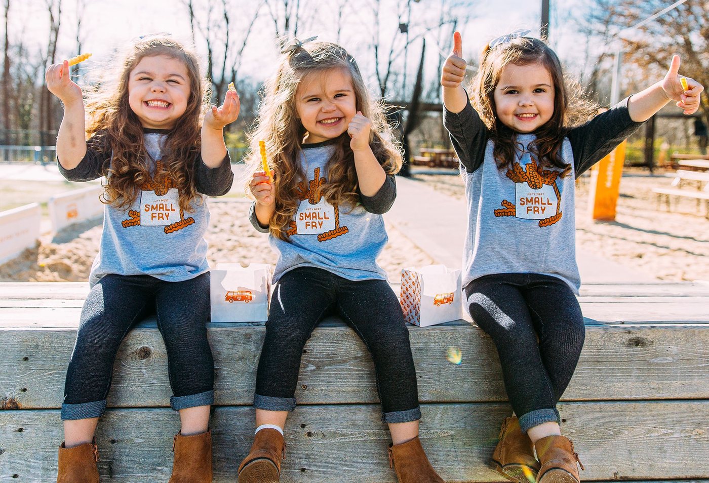 Three kids in Fifty West Small Fry shirts enjoying fries