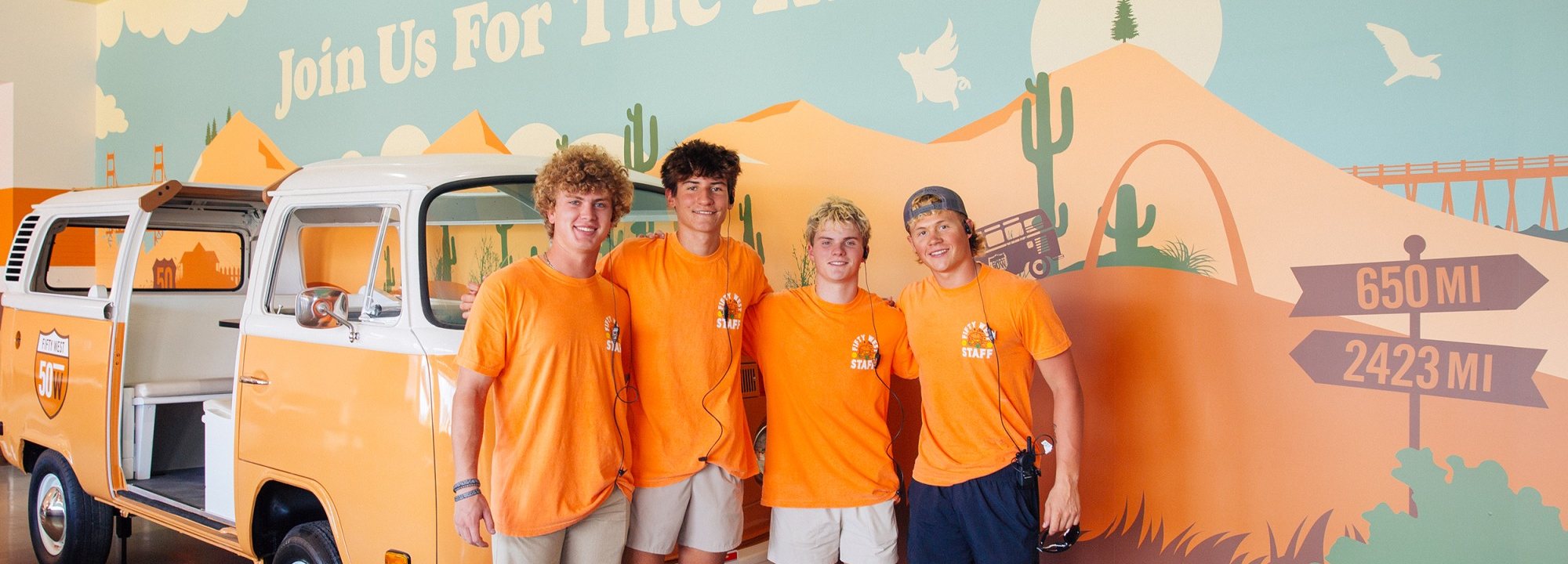 Fifty West staff in matching tees in front of the food truck mural