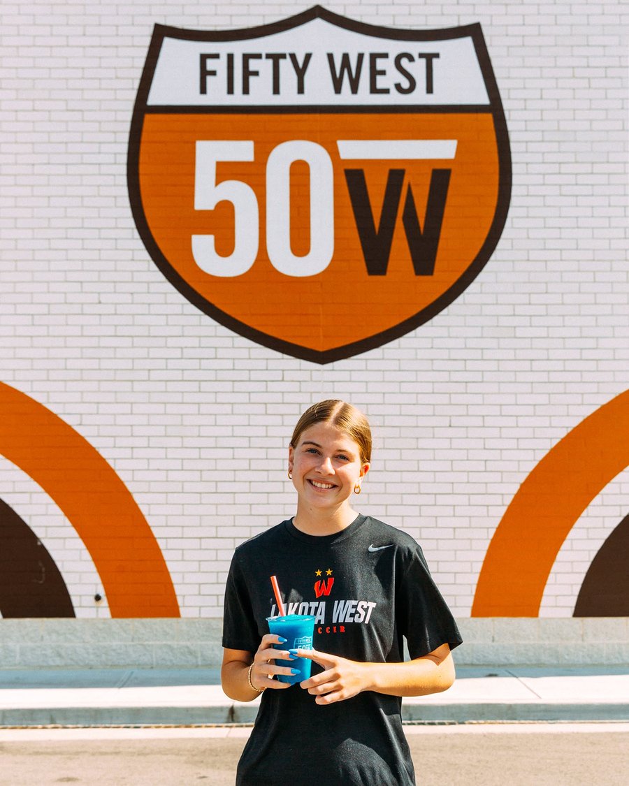 Charlotte Wade, Fifty West Student Athlete of the Month, in front of the Fifty West mural